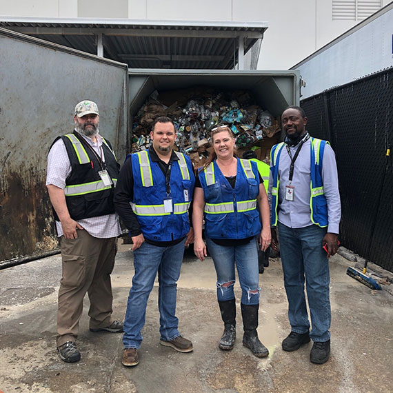UNFI Workers in front of trash disposal unit